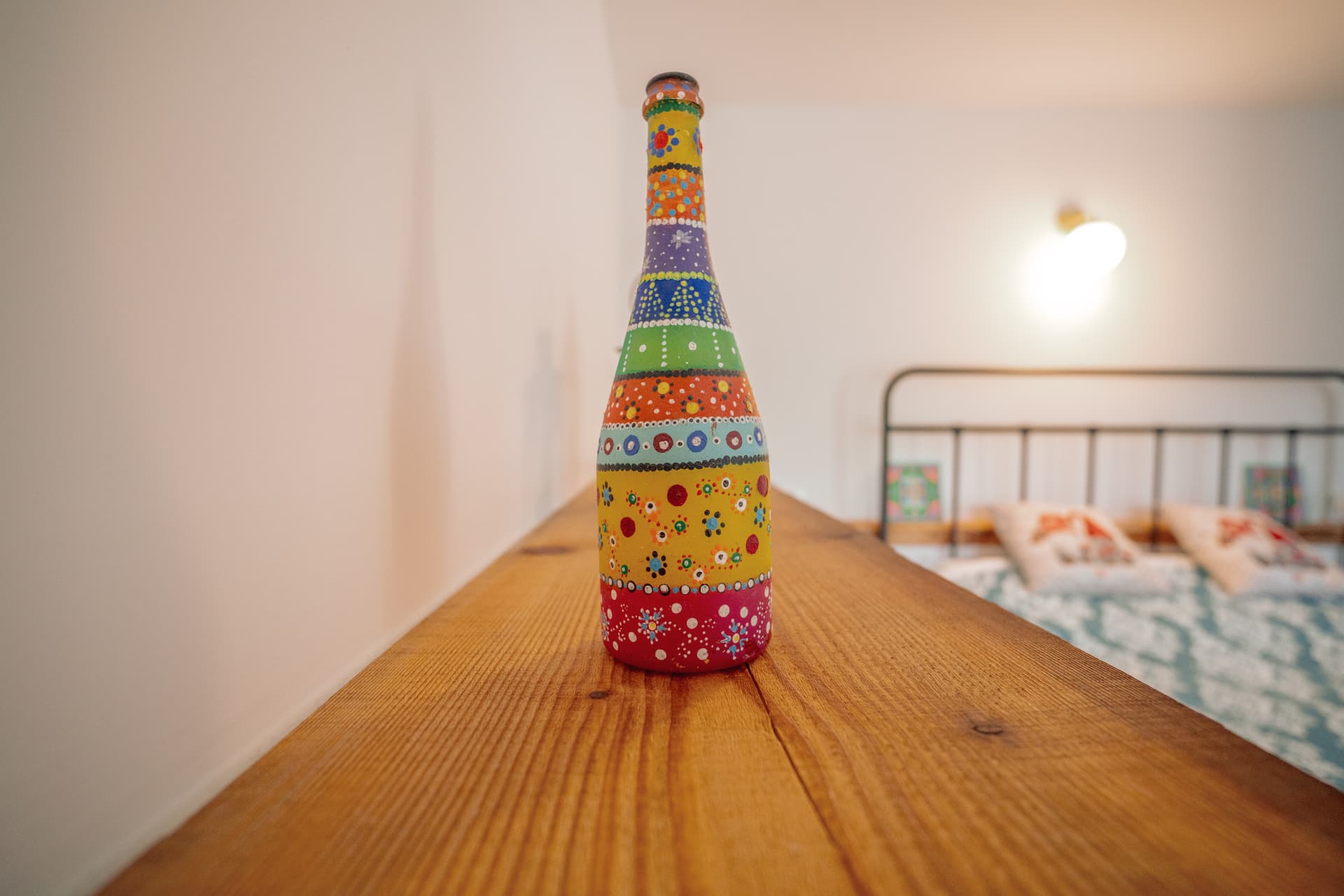 Sticlă pictată manual, cu motive colorate, pe polița de lemn din cameră